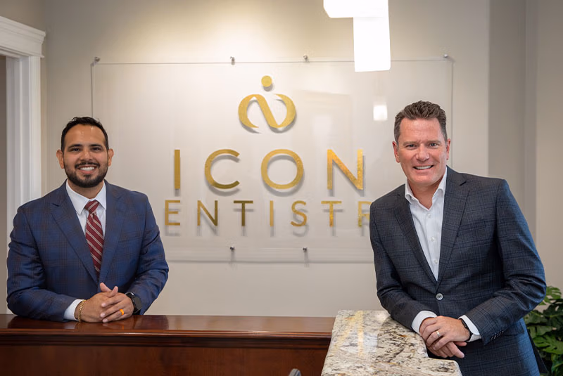 Doctors smiling in front of the Icon Dentistry sign